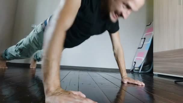 The guy pushed off the floor with a strained tired face. young man trains at home. — Stock Video