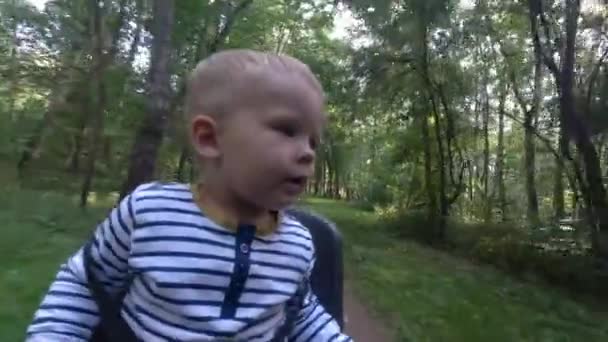 Child boy sitting on bicycle chair while driving and looking around — Stock Video