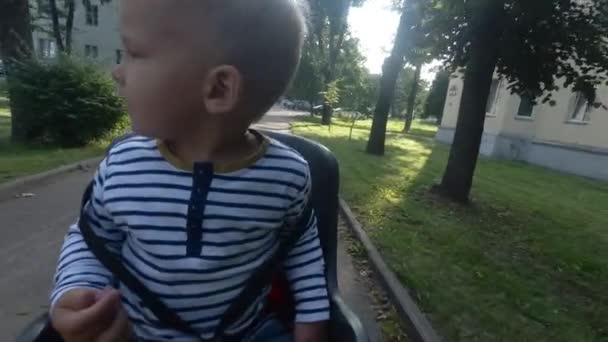 Bambino ragazzo seduto sulla sedia della bicicletta durante la guida e guardarsi intorno — Video Stock