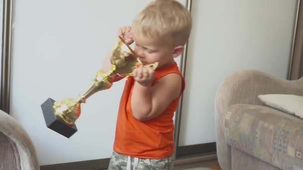 Малыш забавный спортсмен. ребенок с призом. Большая чашка. Концепция успеха и победителя — стоковое видео