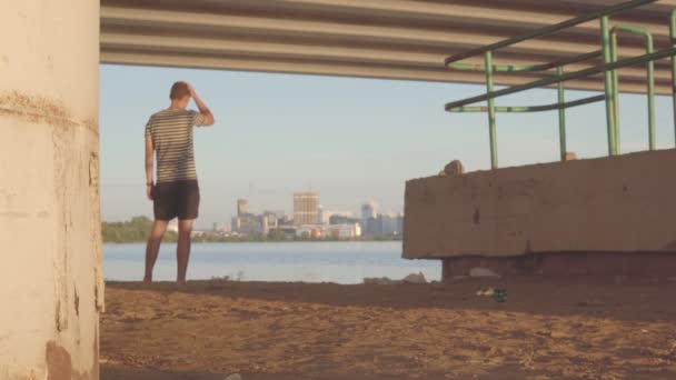 Joven deprimente bajo el puente, en el fondo de la ciudad nocturna — Vídeos de Stock