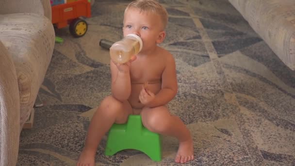 Leuke jongen aanbrengen op een pot thuis, kijken cartoons op de Tv. eten en drinken. — Stockvideo