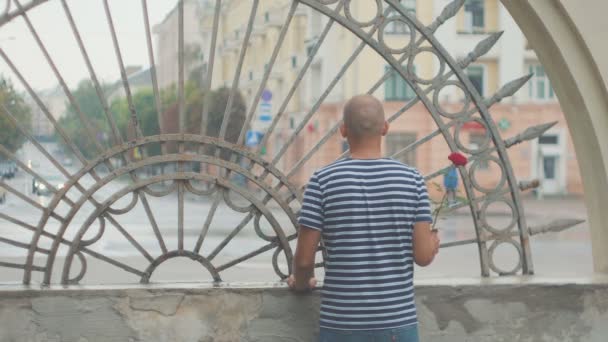 Trieste jonge man met een roos te wachten voor een late vrouw — Stockvideo