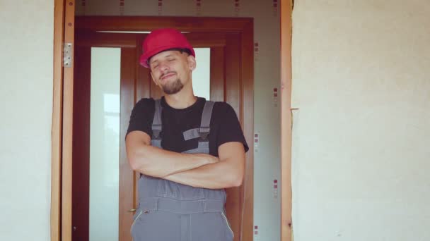 Portrait of cheerful bearded handsome young adult builder on background of a renovated apartment — Stock Video