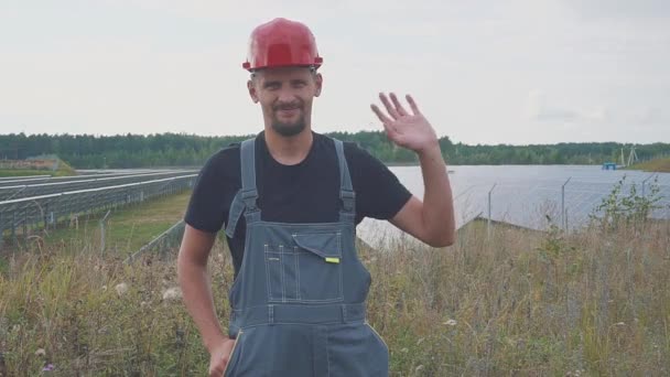 Een werknemer op een zonne-energiecentrale. Glimlachen en zwaaien van zijn hand — Stockvideo