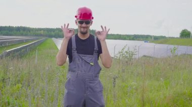 Bir işçi bir güneş güç istasyonu. Gülümseyen ve Tamam, gibi işaret.