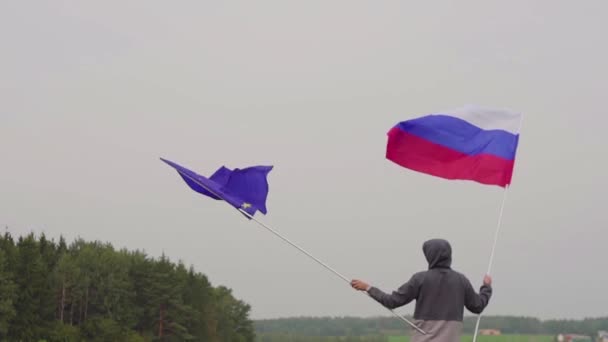 ВИДЕО. Человек с флагами Европейского Союза и России у пейзажа страны. Концепция дружбы и примирения . — стоковое видео