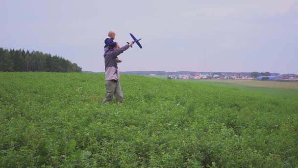 Une famille heureuse. Le garçon sur son père jouant avec un jouet d'avion dans le champ — Video