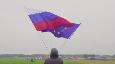 Video. adam Avrupa Birliği ve Rusya bayrakları ülke peyzaj sallıyor. Dostluk ve barış kavramı.