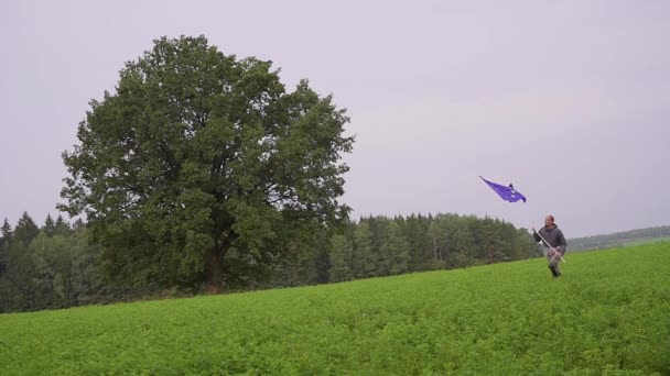 Der Mann läuft mit einer Fahne der Europäischen Union in der Landschaft. Fahnenträger — Stockvideo