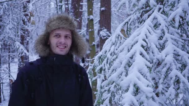 Homem feliz caminha na floresta fria de inverno coberta de neve — Vídeo de Stock