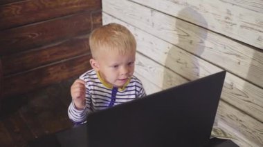 bir bilgisayar ve düşen para ile iki yaşında bir çocuk. dizüstü bilgisayar ve doları banknot hava ile masada oturan boy gülümseyerek. Başarılı iş kavramı
