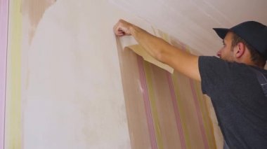 İşçi duvardan duvar kağıdı alır. Evde tamir