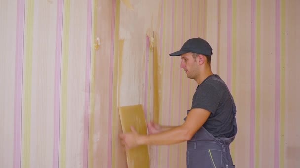 Arbetaren tar tapeter från väggarna. Reparera i lägenheten — Stockvideo