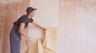 İşçi duvardan duvar kağıdı alır. Evde tamir
