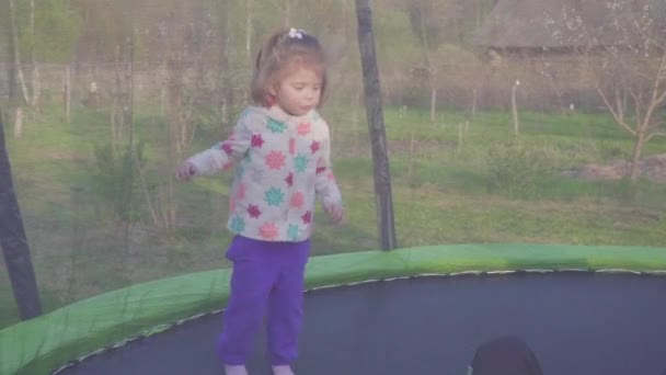 Mutlu üç yaşındaki kız bir trambolin üzerinde atlama. Duygusal neşeli portre. Ağır çekim — Stok video