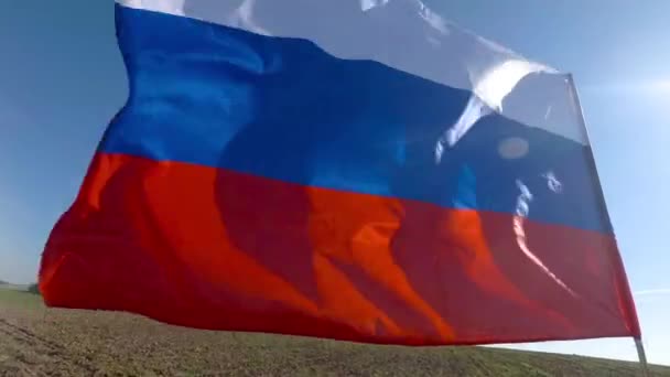 Drapeau tricolore russe flottant au ralenti et contre-éclairé par le soleil dans le paysage — Video