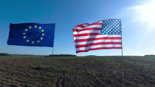 Banderas de los Estados Unidos de América y de la Unión Europea ondeando juntas en el viento. Tiro real en el paisaje. — Vídeos de Stock