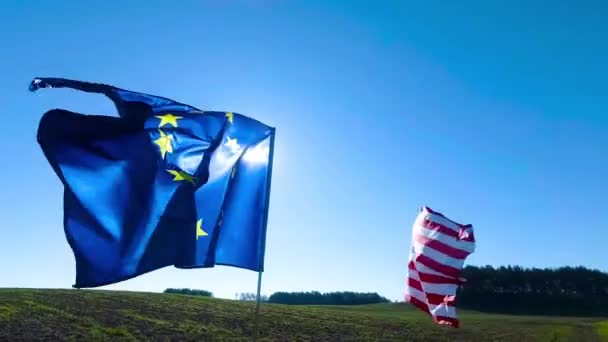 Banderas de los Estados Unidos de América y de la Unión Europea ondeando juntas en el viento. Tiro real en el paisaje. — Vídeo de stock