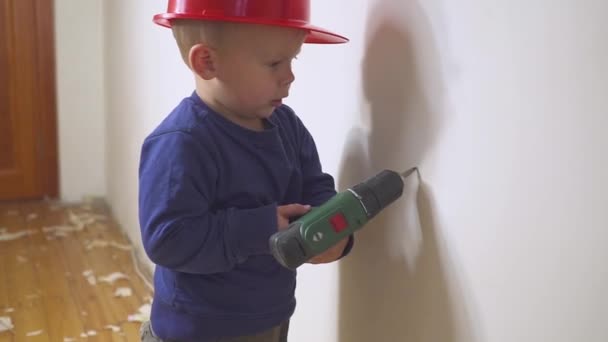 Joven lindo constructor niño en uniforme y casco o casco con destornillador eléctrico contra el fondo de la construcción y la reparación . — Vídeos de Stock