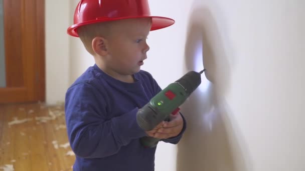 Joven lindo constructor niño en uniforme y casco o casco con destornillador eléctrico contra el fondo de la construcción y la reparación . — Vídeos de Stock