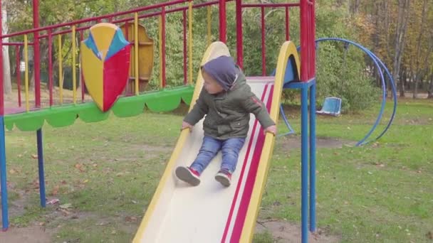 Wesoły chłopak jazdy w dół wzgórza na plac zabaw — Wideo stockowe