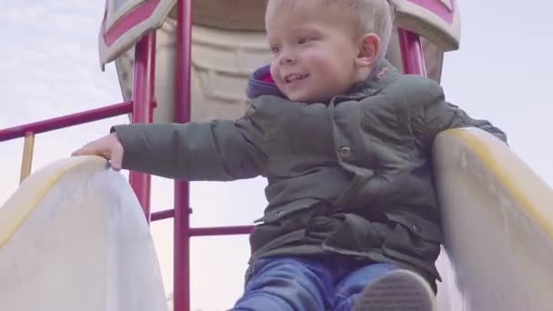 Rapaz alegre descendo a colina no playground — Vídeo de Stock