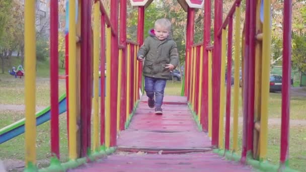 Fröhlicher Junge läuft auf Brücke auf Spielplatz — Stockvideo