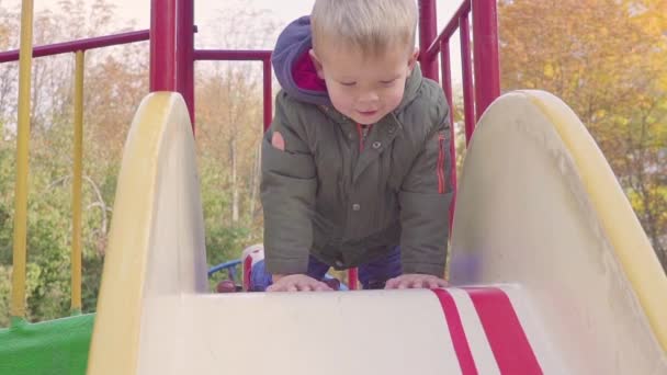 Gladlynt pojke ridning nerför backen på lekplats — Stockvideo