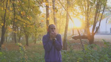 Yakışıklı adam duygu eller, soğuk ve ısınma adam sonbahar parkta donuyor. soğuk.