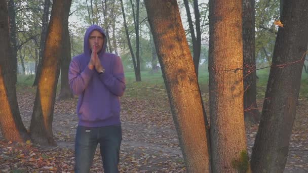 Jóképű férfi érzés hideg és felmelegedés kezét, az ember lefagy az őszi parkban. hidegen. — Stock videók