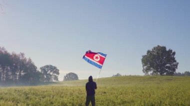Kuzey Kore bayrağı sallayarak peyzaj başarılı siluet adam.