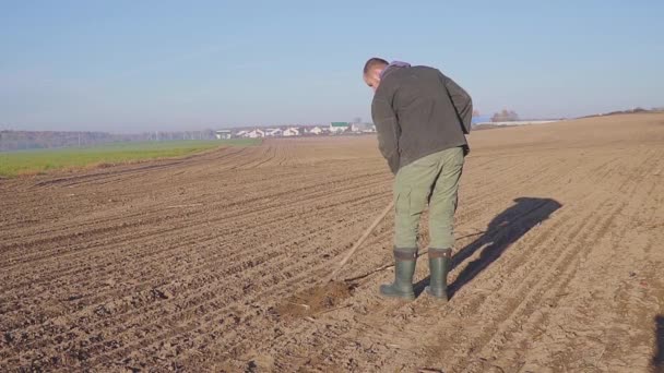 El hombre cultivar manualmente la tierra con una azada día soleado — Vídeo de stock