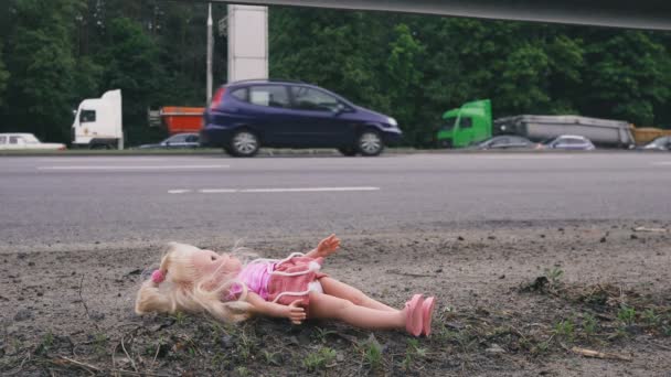 La muñeca se encuentra cerca de la carretera con tráfico activo. Muchos coches vienen por detrás. . — Vídeos de Stock