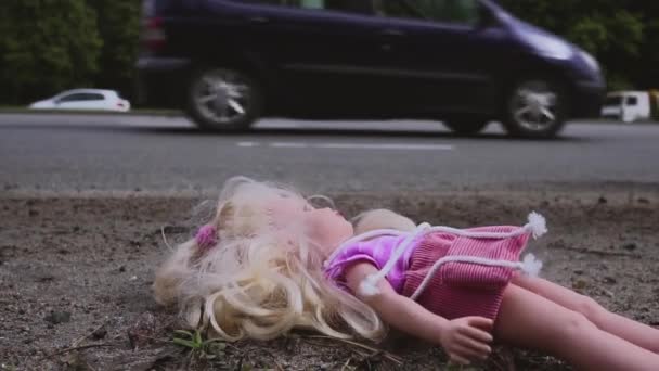 The doll falls near the road with active traffic. Many cars are coming from behind. Slow motion. — Stock Video