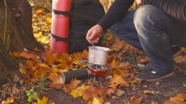 adam yiyecek ya da bir gaz sobası yakın göl sonbahar ormandaki üzerinde sıcak içecek aşçılar