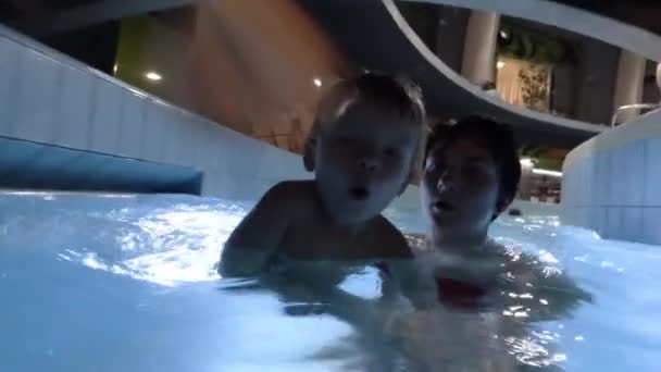 Happy young mother holding baby son on arms, smiling and playing with him in swimming pool. — Stock Video