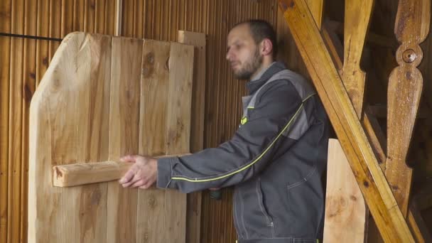 Рабочий сам устанавливает дверь в деревянном интерьере — стоковое видео
