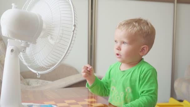 Infância, conceito de casa - menino bonito com grande ventilador de refrigeração — Vídeo de Stock