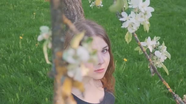 Joven mujer feliz caminando en un huerto de manzanas en las flores de primavera blanco. Retrato de una hermosa chica — Vídeos de Stock