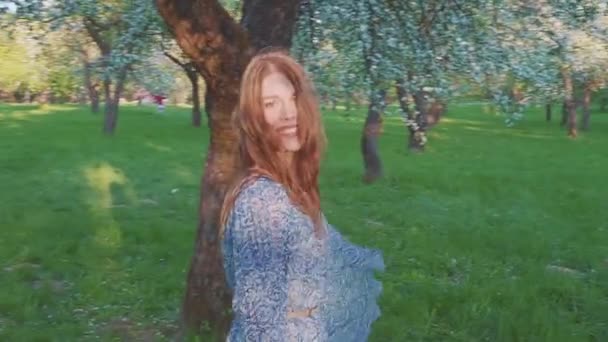 Verleidelijk jonge vrouw lopen in een appelboomgaard in de Lentebloemen wit. Portret van een mooi meisje in de avond groente tuin. — Stockvideo