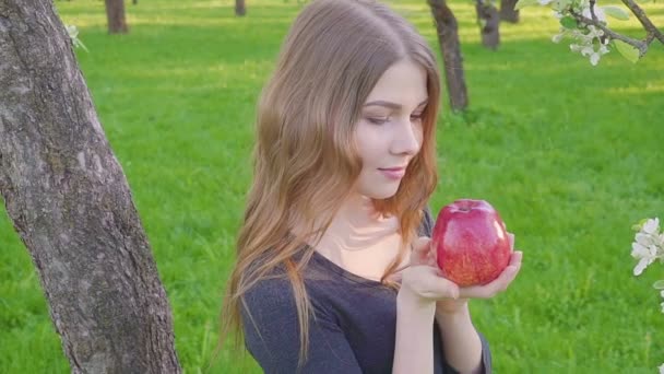 Retrato de rosto jovem bela mulher segurando maçã na primavera florescendo macieira fundo verão natureza. estação de primavera — Vídeo de Stock