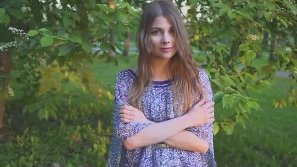 Retrato de chica atractiva joven con una hermosa sonrisa. el modelo mira a la cámara y sonríe. chica en un brillante vestido de verano en el Parque . — Vídeo de stock