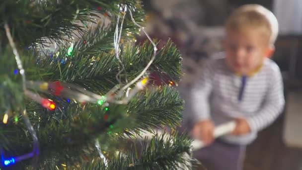 Junge spielt mit gespendetem Fahrrad in der Nähe des Weihnachtsbaums — Stockvideo