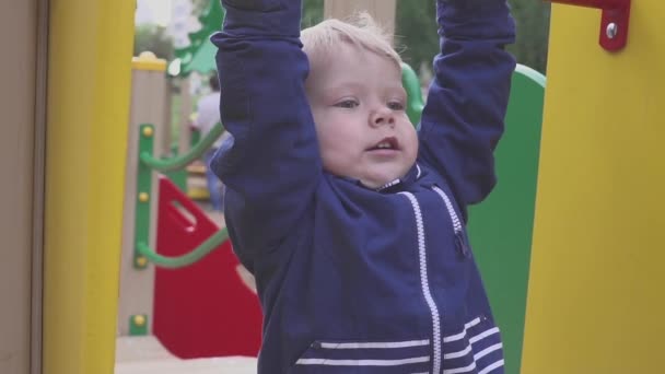 De jongen wordt gespeeld op een speelplaats in een park of kleuterschool. Het kind is leuk om te stoeien. — Stockvideo