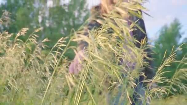 Рука дівчини в камуфляжній куртці в селі торкається рослини — стокове відео