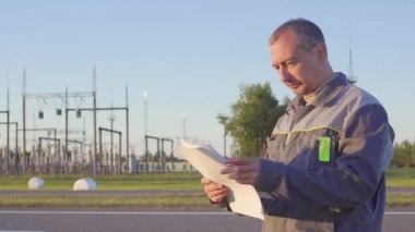 Mühendisi ve elektrik alt istasyonlar görevli. İşçi planları ve elektrik alt istasyonlar toplantıda içinde clipboard ile.