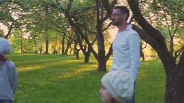 Anne ve iki kızı top bahar parkta blooming Orchard oynamaya. Etkin boş.
