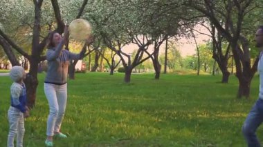Anne ve iki kızı top bahar parkta blooming Orchard oynamaya. Etkin boş.
