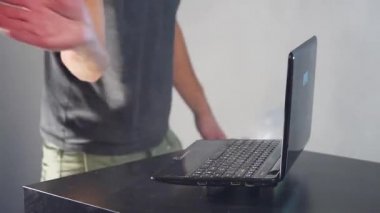 Adamın elleri ve parmakları kırılmış dizüstü bilgisayarda. Odada duman.